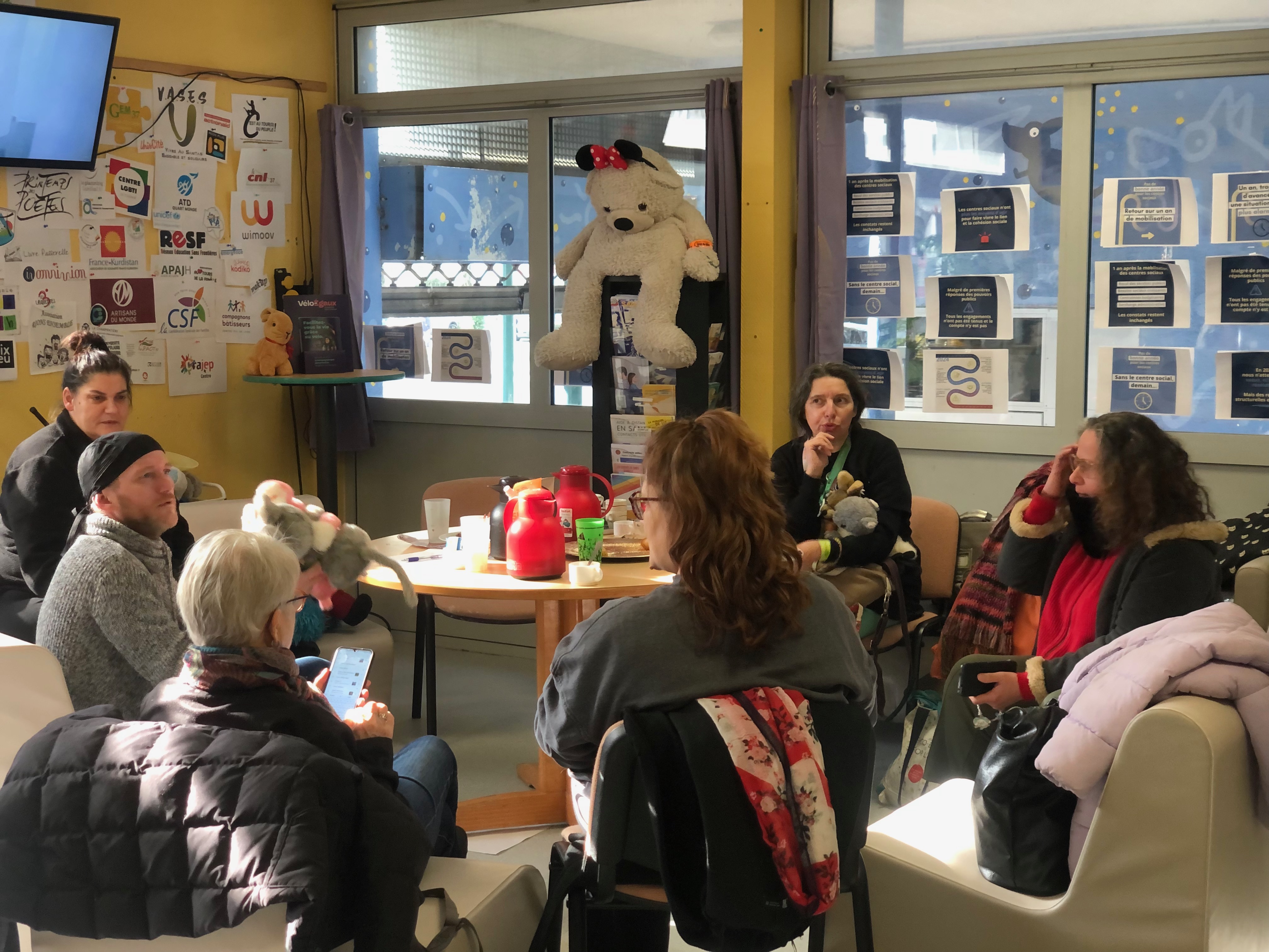 Une réunion dans un local. Une dizaine de personnes assises autour d'une table. 