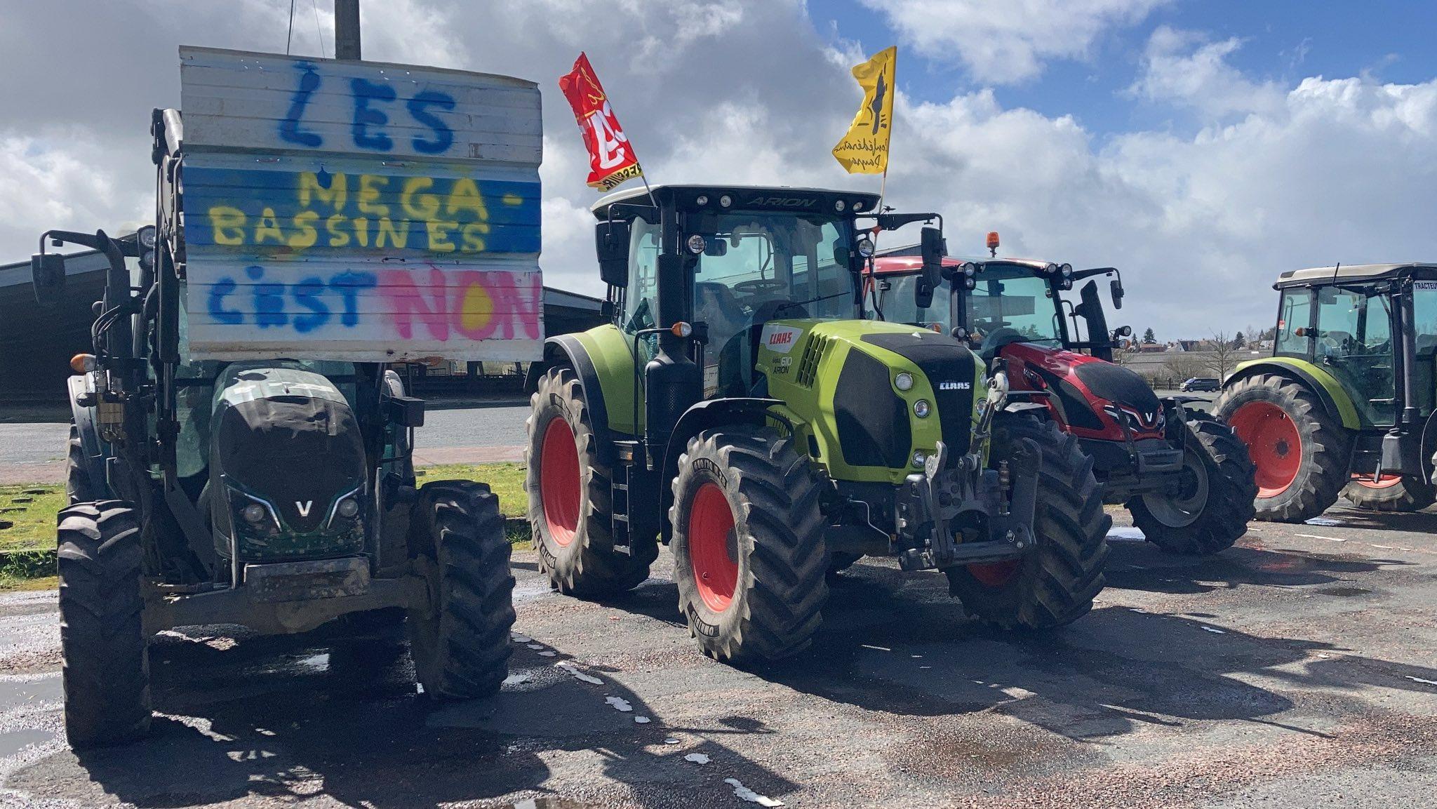 Des tracteurs alignés dont un arbore une pancarte "les mégabassines c'est non"