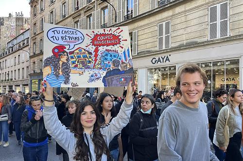 une jeune femme porte une pancarte "tu casses tu répares" en faisan référence aux coupes budgétaires