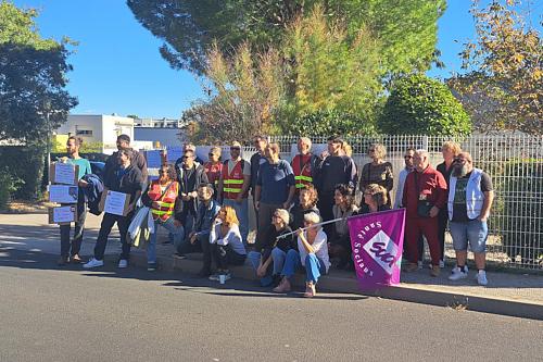 Des personnes rassemblée posent pour une photo avec des chasubles et des drapeaux de Sud Santé sociaux. 