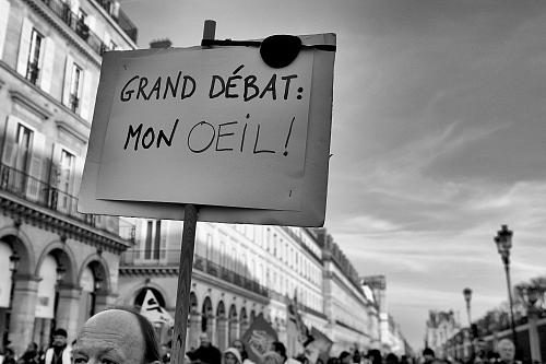 Un homme porte une pancarte "grand débat, mon oeil"