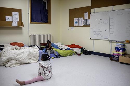 une petite fille dans une salle de classe avec des matelas au sol 
