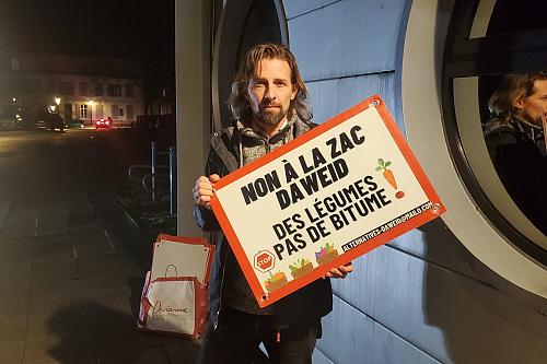 Un homme tient une pancarte "Non à la Zac Daweid, des légumes, pas de bitume!"