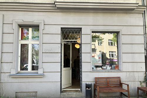 Un local avec une porte ouverte, un banc devant. 
