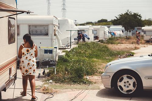Une femme de dos et des caravanes sur une aire d'accueil.