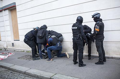 Des policiers dont certains en civil arrêtent deux personnes dans une rue.