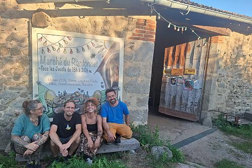 Quatre personnes souriantes assises sur le seuil d'un bâtiment.