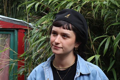 Une jeune femme sourit, un béret sur la tête.
