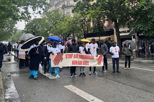 Des personnes marchent dans la rue avec une banderole "Stop aux embrouilles. Non aux rixes"
