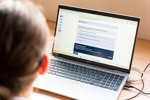 Un salarié est pris en photo de dos face à un écran d'ordinateur portable.