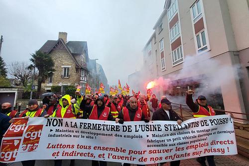 La tête du cortège d'une manifestation : des manifestants portent une banderole "Non à la fermeture de l'usine Stellantis de Poissy".