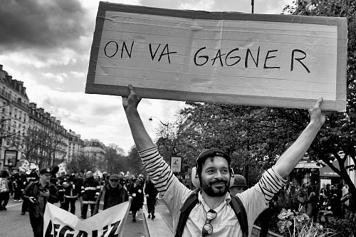 un homme debout dans une manifestation tient une pancarte "on va gagner"