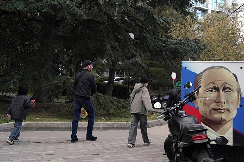 Une peinture représentant Vladimir Poutine sur fonds rouge, blanc et bleu, dans une rue.