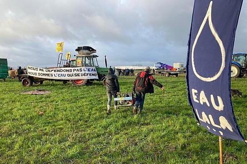 banderole "eau la la" et "nous ne défendons pas l'eau, nous sommes l'eau qui se défend" avec un drapeau de la confédération paysanne sur un tracteur