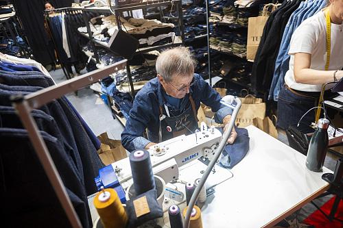 Un ouvrier textile en train de repriser un jean devant sa machine à coudre