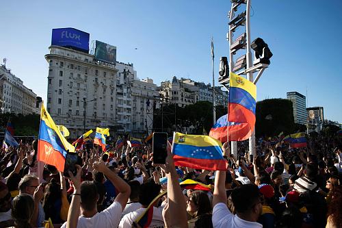 Un rassemblement sur une place, les personnes portent des drapeaux du Venezuela. 