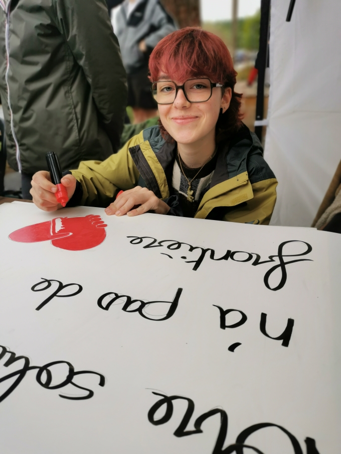 une jeune dessine un coeur sur un grand carton.
