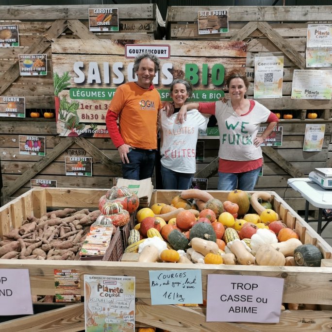 trois femmes et hommes derrière un étal de fruits et légumes bio