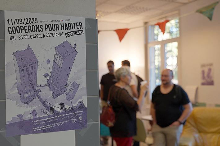 Une affiche "Coopérons pour habiter" collées sur un poteaux lors d'un événements où des personnes discutent débout au deuxième plan.