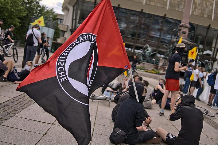 Un drapeau antifasciste tenu par une personne assise par terre