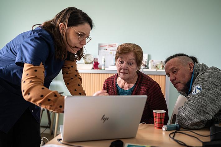 une infirmière et deux patients autour d'un ordinateur