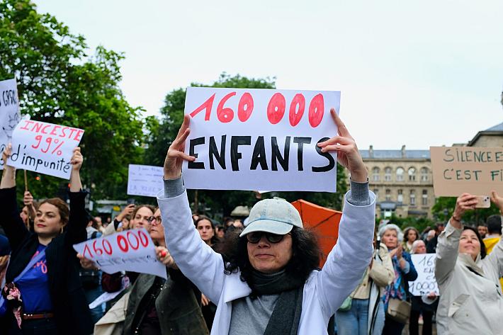 Une femme dans une manifestation brandit une pancarte sur laquelle il est écrit "160 000 enfants".