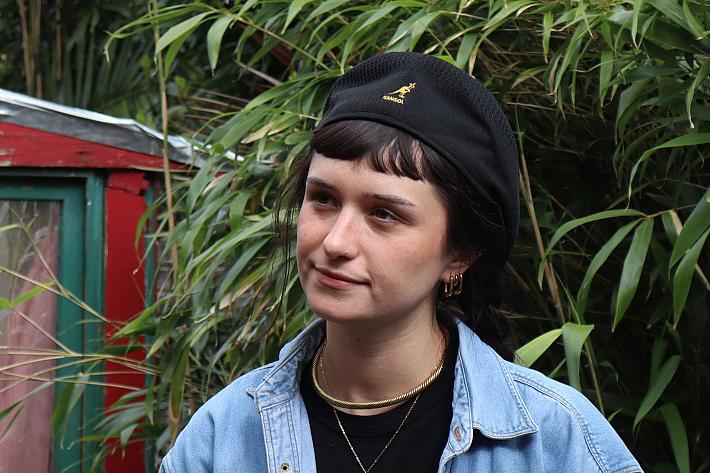 Une jeune femme sourit, un béret sur la tête.