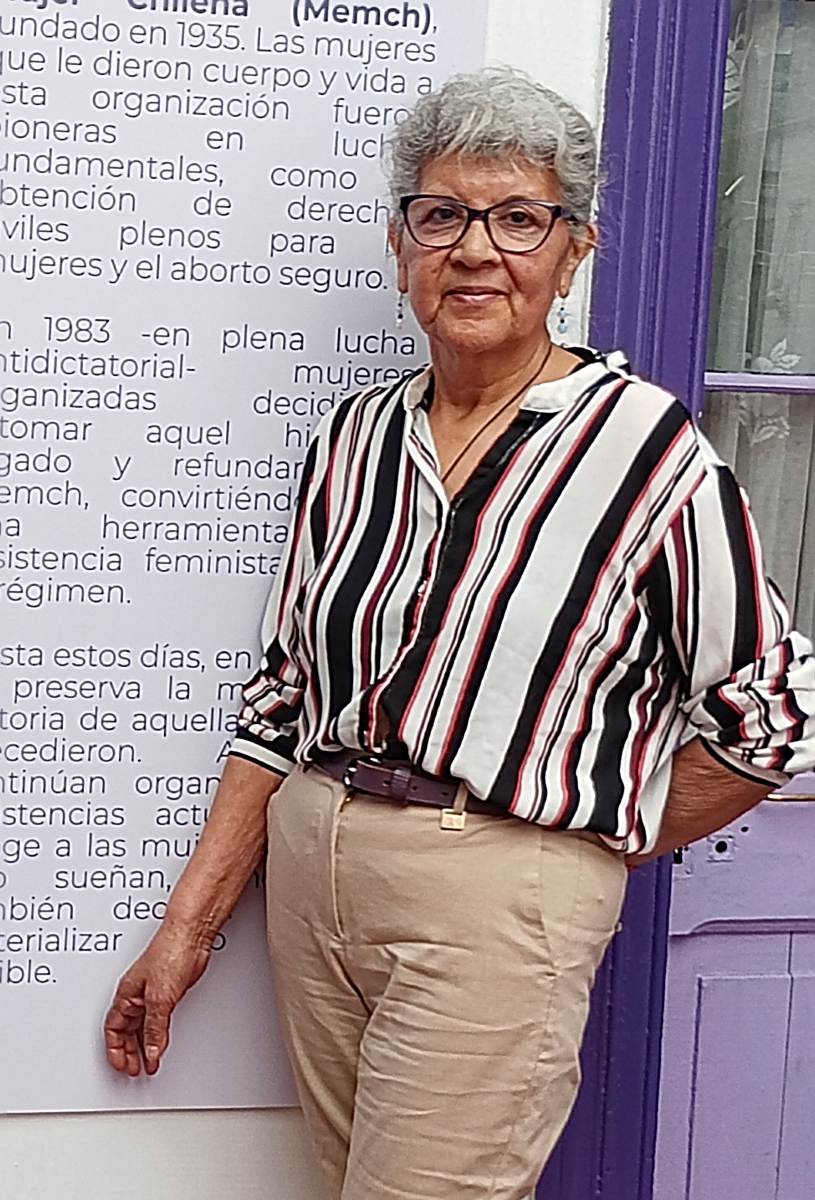 Une femme debout en chemise et pantalon.