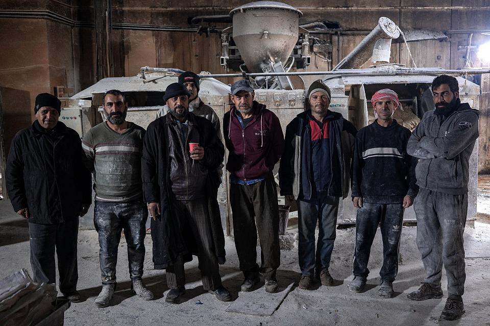 Huit hommes debout dans un bâtiment. 