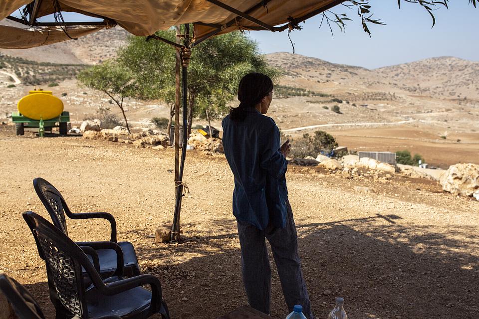 Tina, à l'ombre, face à des collines arides