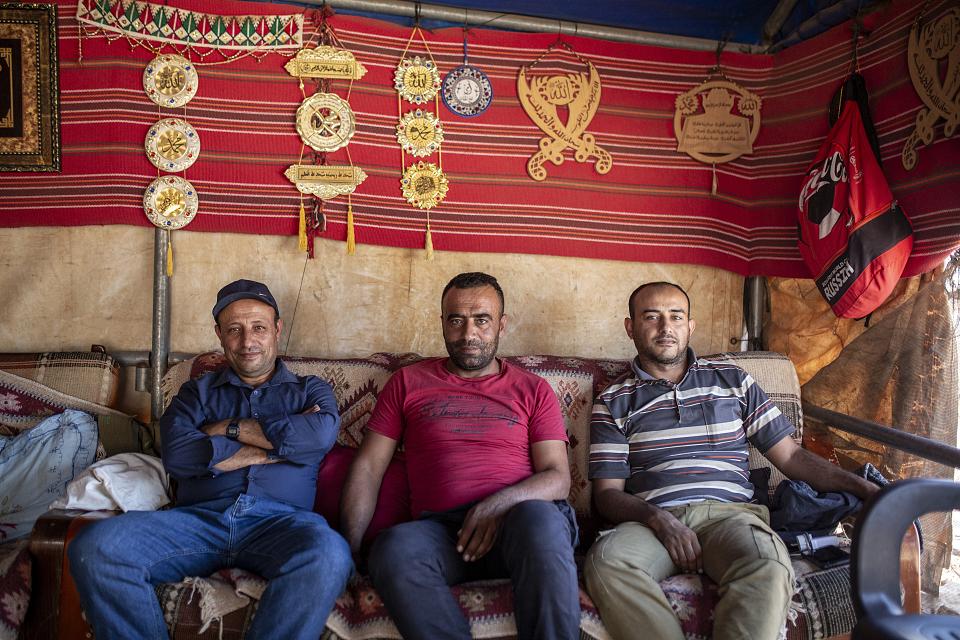 Les trois hommes sont assis sous une grande tente, d'où ils surveillent leur troupeau