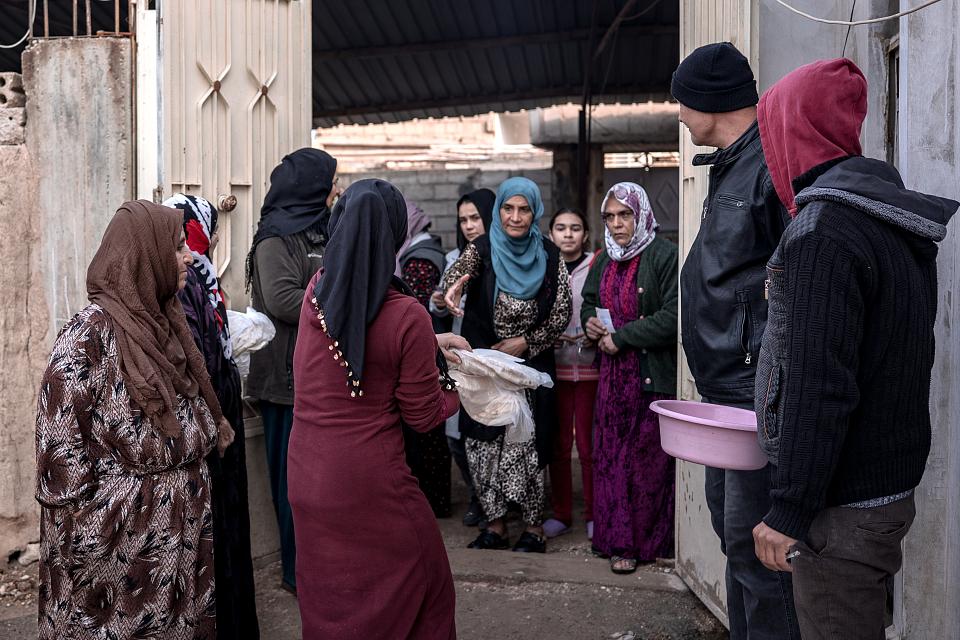 La famille distribuant du pain à l'entrée d'un hangar.