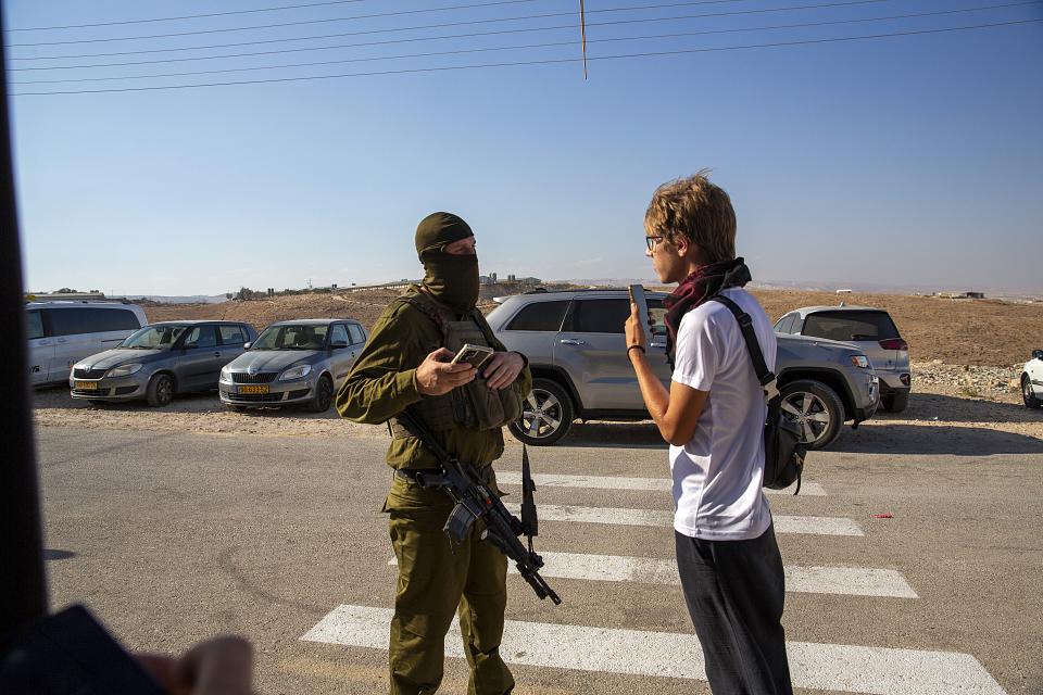 Le journaliste, sur une route, face à un soldat israélien cagoulé, en uniforme et armé