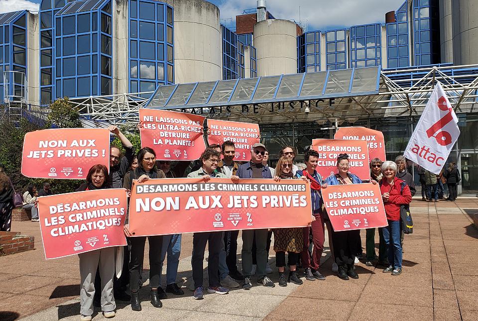 Des activistes portent des banderoles devant le tribunal sur lesquelles ont peut notamment lire "non aux jets privés"