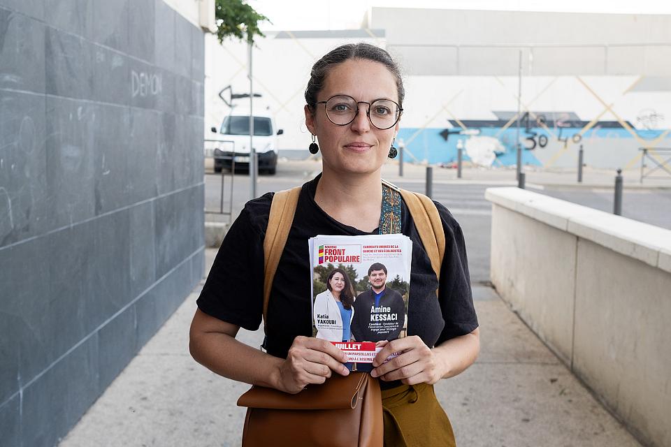 Une femme avec des lunettes montre un tract du Nouveau Front Populaire