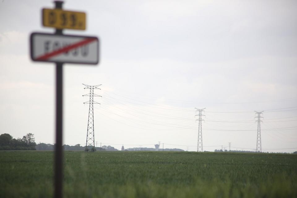 Le panneau barré de la commune Fouju au premeir plan devant des lignes électrique au second plan. 