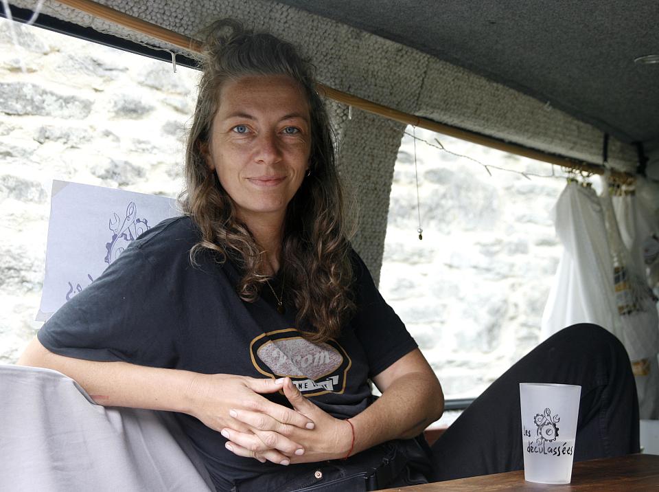 Une femme assises dans ce qui ressemble à l'arrière d'un van regarde l'objectif