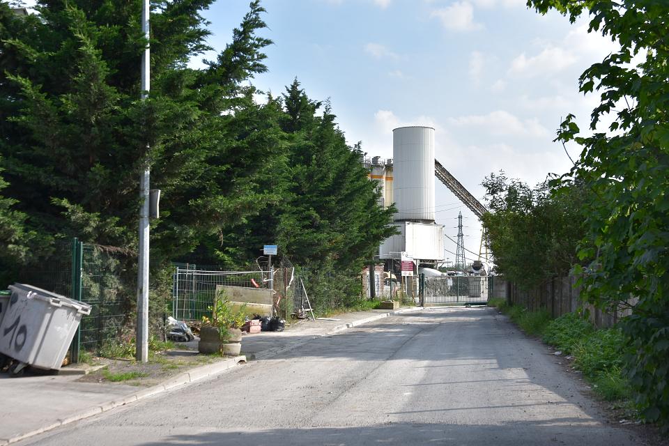 Une reube avec au fond un bâtiment industriel 