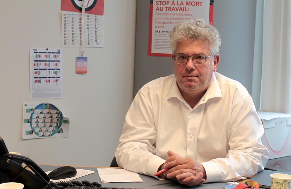 Un homme assis à un bureau regarde l'objectif.