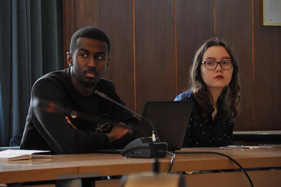 Un jeune homme et une jeuen femme, assis, écoutent attentivement. 
