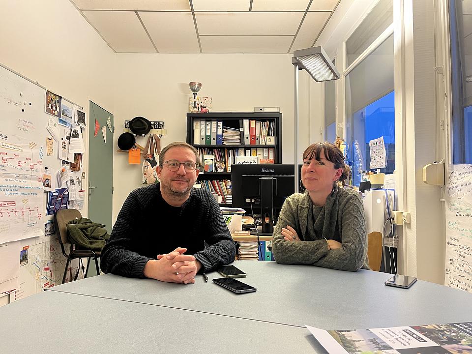 Deux personnes assises à une table, souriants, dans un bureau. 