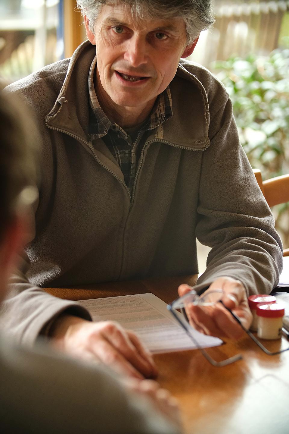 Un homme, lunettes à la main, s'exprime à une table