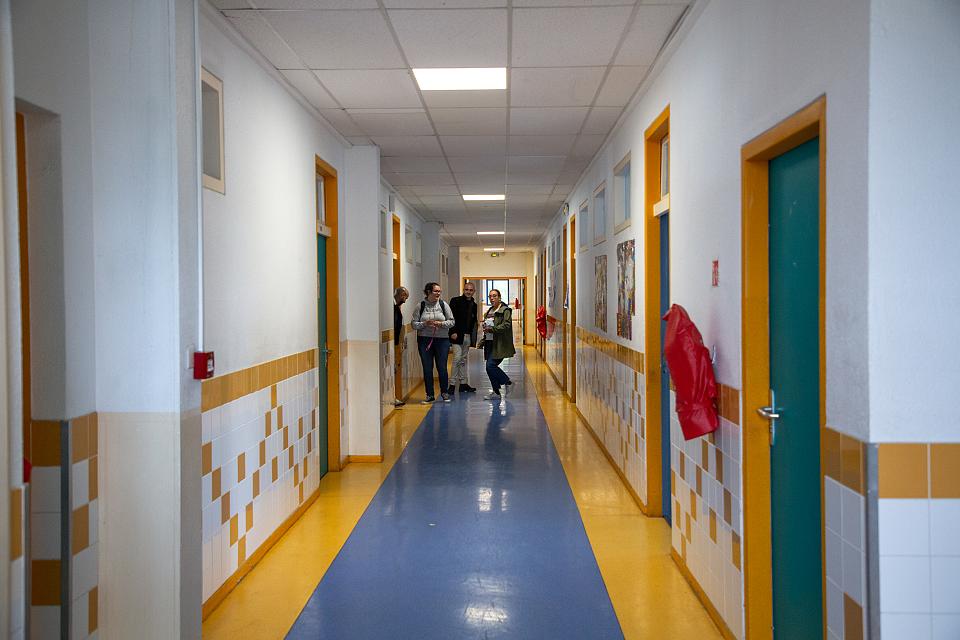 Un couloir bleu et jaune, trois élèves au fond.