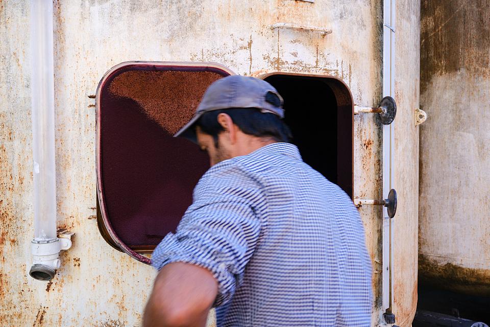 Un homme jeune de dos devant une g-haute cuve en métal. 