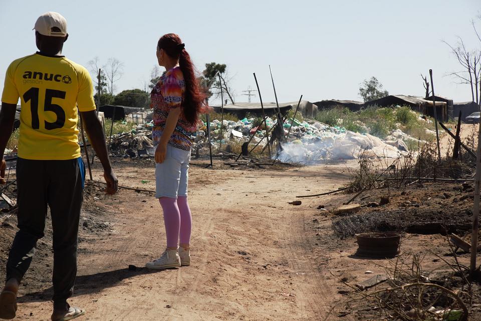 Un homme et une femme de dos regardent un terrain avec des débris. 
