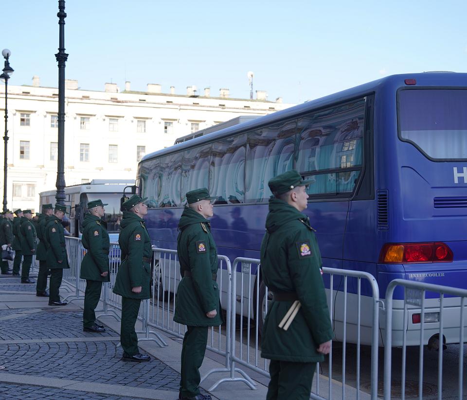 Des hommes en uniforme militaure debout en rang devant un bus. 