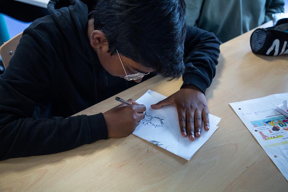 Un élève dessine sur une feuille