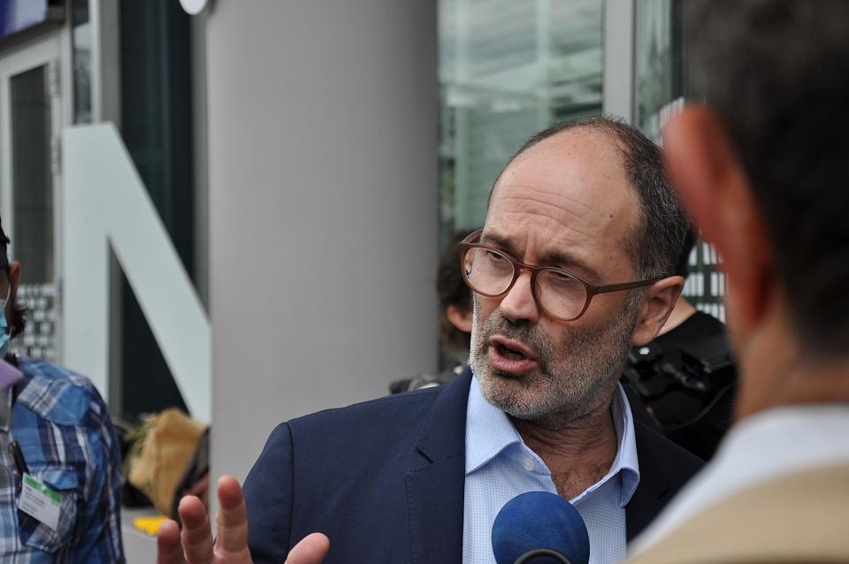 Un homme en chemise et veste parle à un micro.