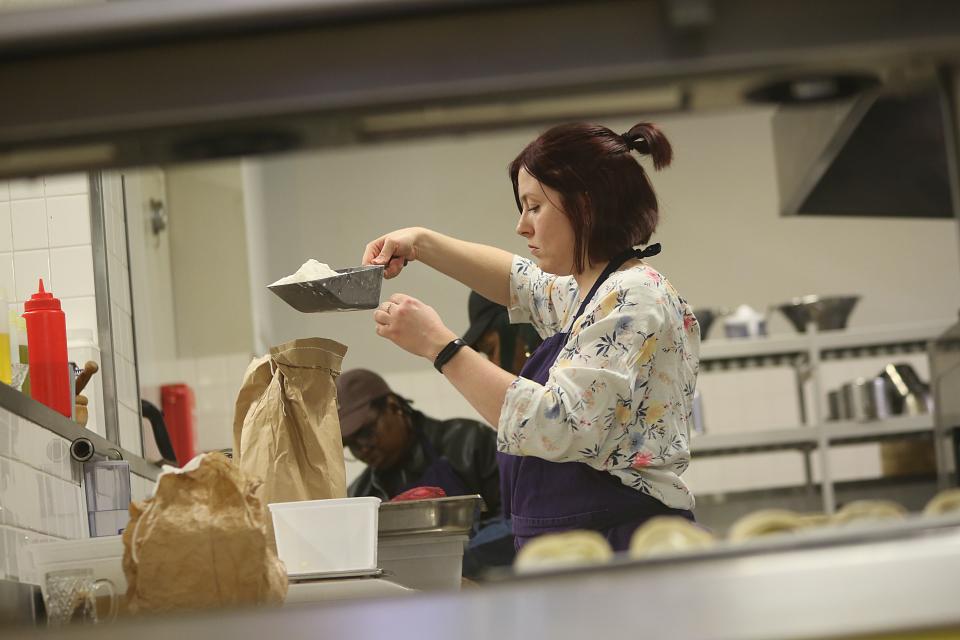 Une jeune femme pèse de la farine en cuisine.