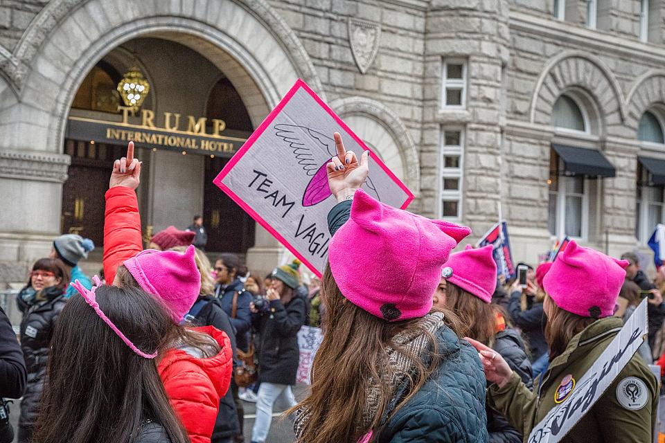 Des femmes au bonnet rose font des doigts d'honneur devant le bâtiment du Trump international hotel.